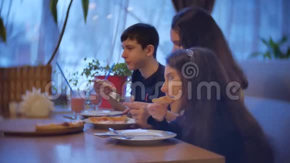 孩子们一家人在咖啡馆里吃披萨青少年在室内咖啡厅吃快餐慢动作视频的预览图
