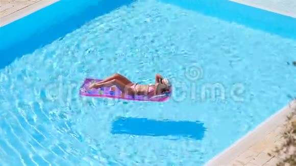 大泳池里穿比基尼充气床垫的年轻女子视频的预览图