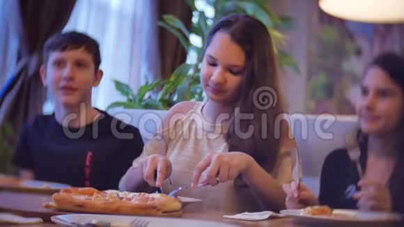 一家群孩子在咖啡馆里吃披萨青少年在室内吃快餐在咖啡馆慢动作视频的预览图