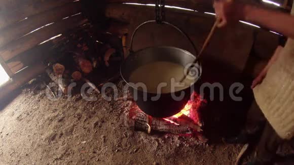 农夫把木头放在木屋里的锅下放在火上视频的预览图