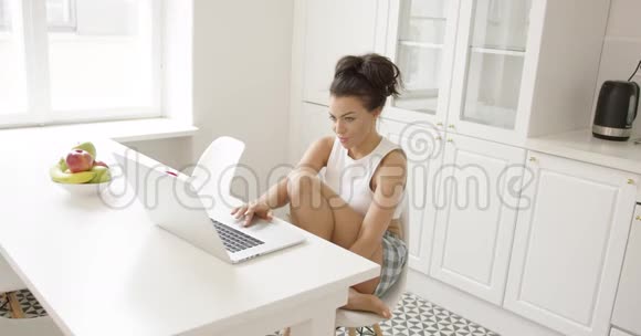 小女孩在厨房里用笔记本电脑视频的预览图