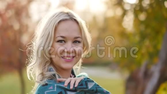 年轻漂亮的金发女郎在一个带有黄昏灯光的秋天公园的背景下慢动作视频的预览图