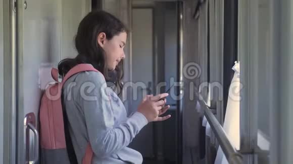 小女孩带着背包和智能手机在火车车厢里散步旅游运输铁路概念视频的预览图