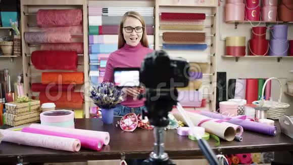 快乐的年轻女子作为花店花店的花匠设计并布置花圈花束花瓶视频的预览图