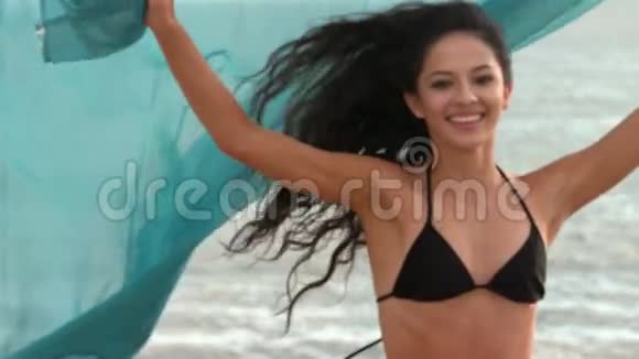 快乐的女人拿着围巾在海滩上奔跑视频的预览图