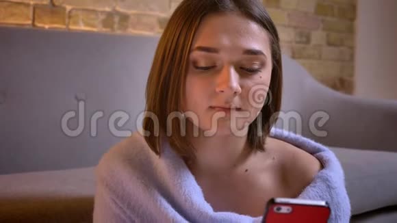 年轻美丽的白种人女性用手机看着镜头微笑的特写镜头视频的预览图