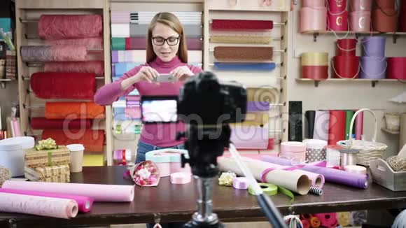 快乐的年轻女子作为花店花店的花匠设计并布置花圈花束花瓶视频的预览图