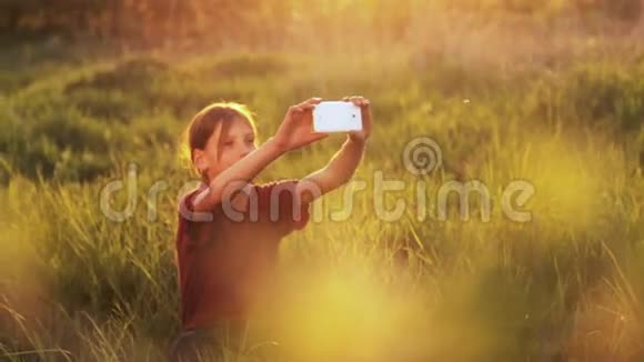 带着电话的白人男孩日落时分带着智能手机的少年有电话照片的男孩日落视频的预览图
