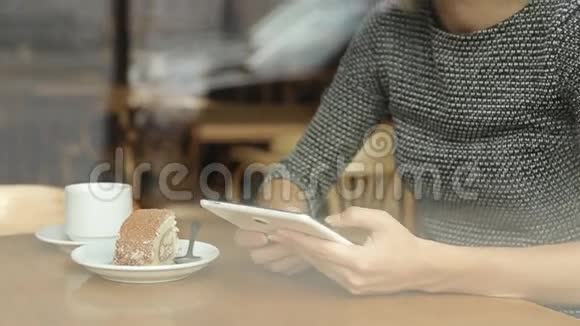 坐在咖啡馆里的年轻漂亮的女士带着平板电脑视频的预览图