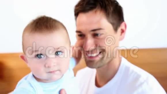 快乐的父亲和小儿子坐在床上视频的预览图