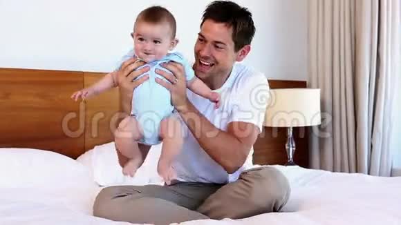 快乐的父亲和小儿子坐在床上视频的预览图