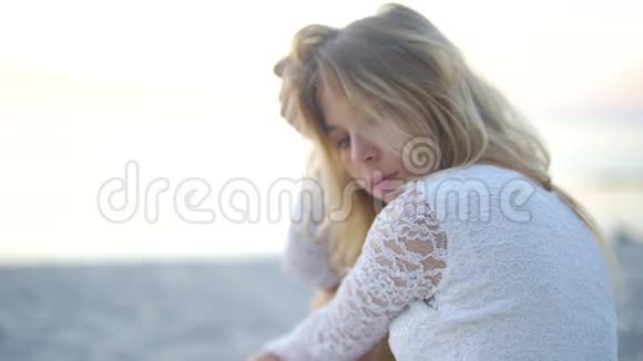 美女特写拍摄看着大海和照相机在黄金时间被推在海滩上情绪化的脸视频的预览图
