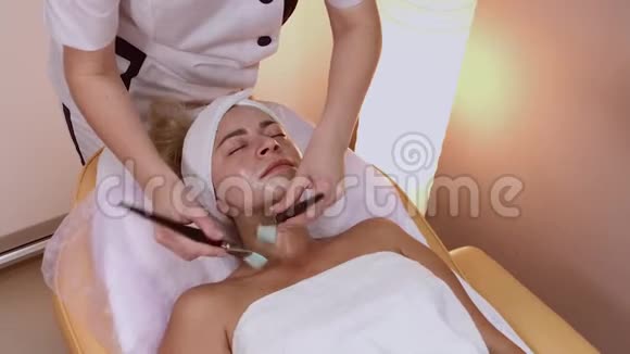 专业美容师在女人脸上涂上刷子的面膜视频的预览图