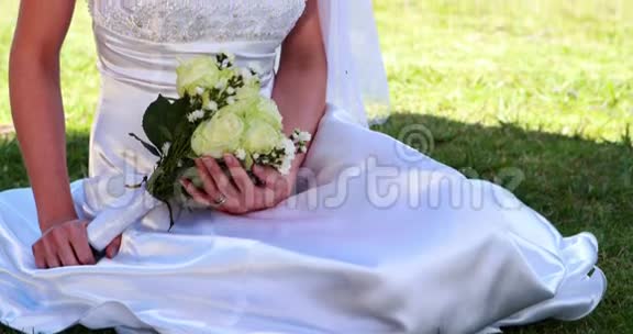 微笑的新娘坐在草地上视频的预览图