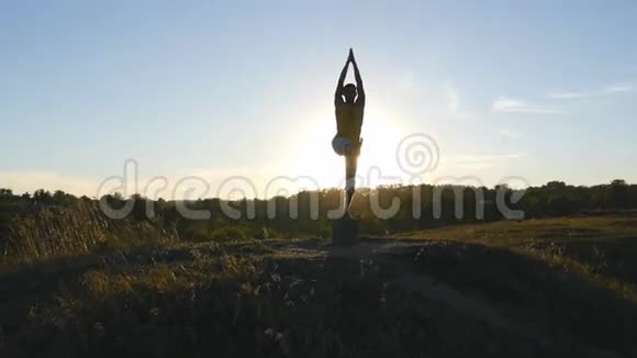 瑜伽在大自然中练习瑜伽动作和姿势站在户外瑜伽姿势的运动男子剪影运动员视频的预览图