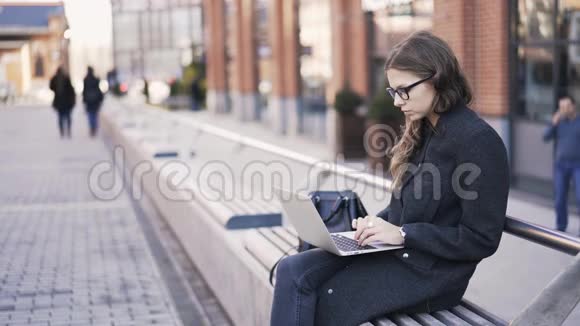 女人在街上用笔记本电脑打字视频的预览图