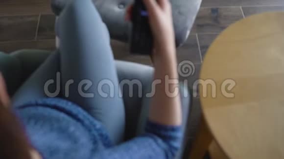 女人坐在椅子上用绿色的屏幕看电视用遥控器切换频道铬键视频的预览图