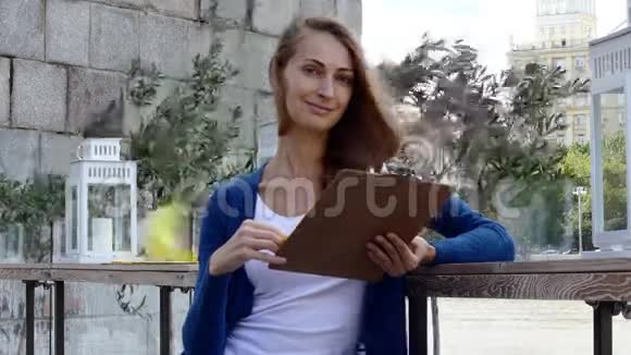 年轻快乐的女人在街边咖啡馆看菜单视频的预览图