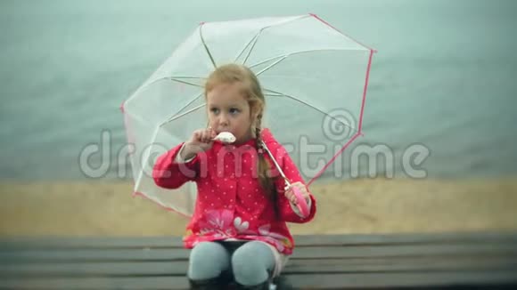 小女孩带着雨伞在雨中玩耍在海岸吃冰淇淋视频的预览图