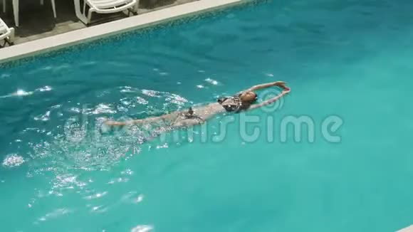 女孩穿着黑色泳衣在酒店的室外游泳池游泳视频的预览图