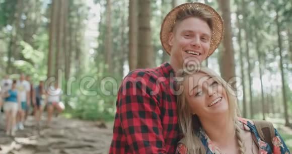 微笑的夫妇在树林里放松时看着相机视频的预览图