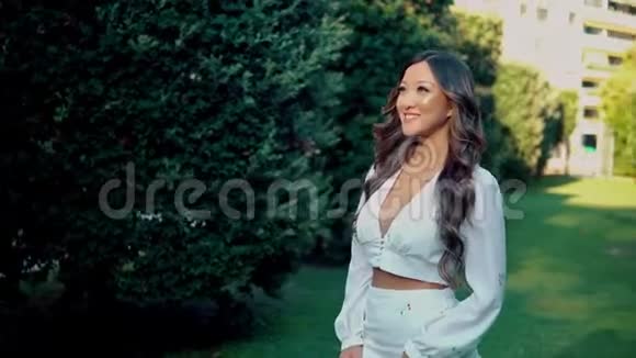美丽的亚洲女孩穿着白色连衣裙在公园里微笑视频的预览图