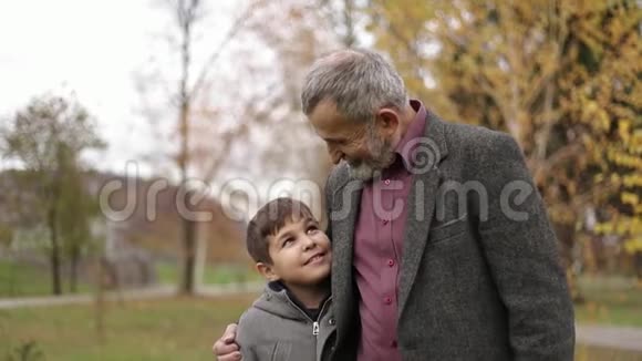爷爷和孙子一起在公园里度过时光他们正在公园里散步兴高采烈视频的预览图