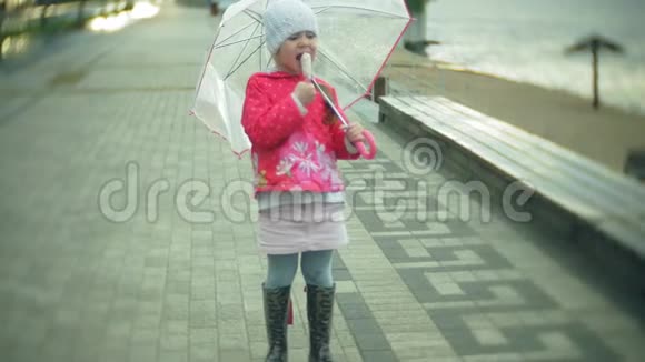 小女孩带着雨伞在雨中玩耍在海岸吃冰淇淋视频的预览图