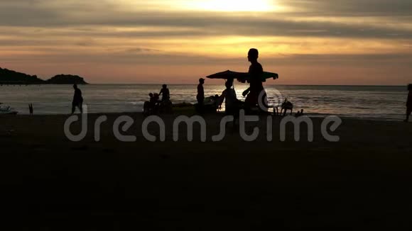 日落时人们在夏日海滩散步的剪影视频的预览图