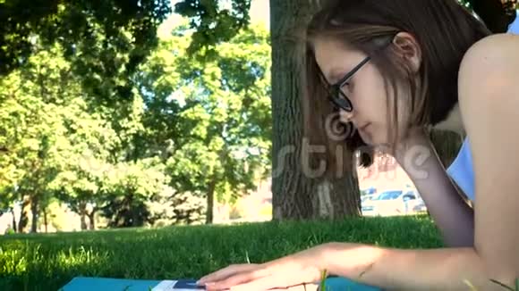 女孩躺在公园的草地上看书视频的预览图