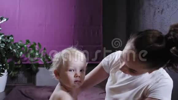 婴儿按摩妈妈或治疗师在家给宝宝做足底按摩保健和医药理念金发男孩视频的预览图