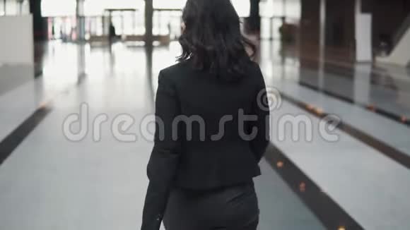 一个女商人从一个现代商业中心的旋转门离开穿西装的女孩看手表视频的预览图
