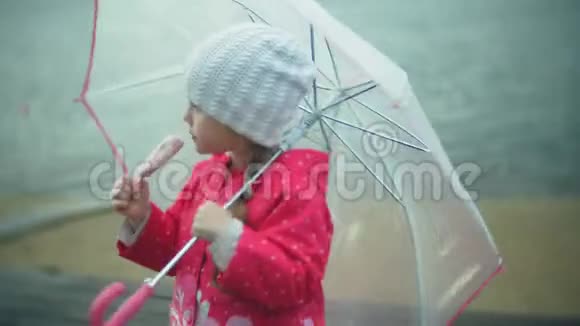 小女孩带着雨伞在雨中玩耍在海岸吃冰淇淋视频的预览图