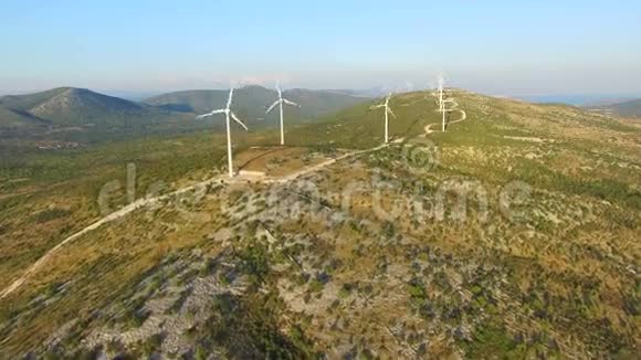 在绿色山丘上的优雅生态风力涡轮机之上飞行视频的预览图