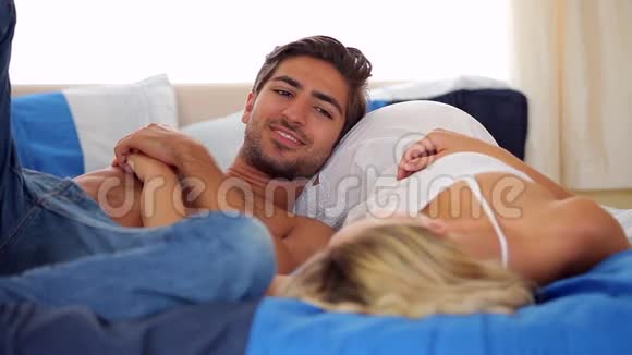 可爱的年轻夫妇躺在床上聊天视频的预览图
