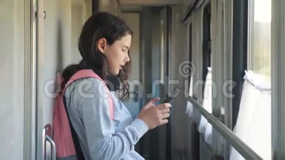 小女孩带着背包和智能手机在火车车厢里散步旅游运输铁路概念视频的预览图
