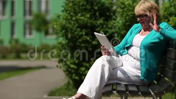 女人坐在长凳上通过平板电脑交流视频的预览图