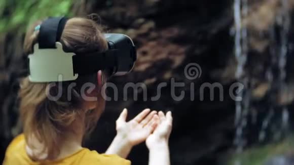 女孩虚拟现实眼镜VR晴天野生动物女人举手山瀑布森林电子视频的预览图
