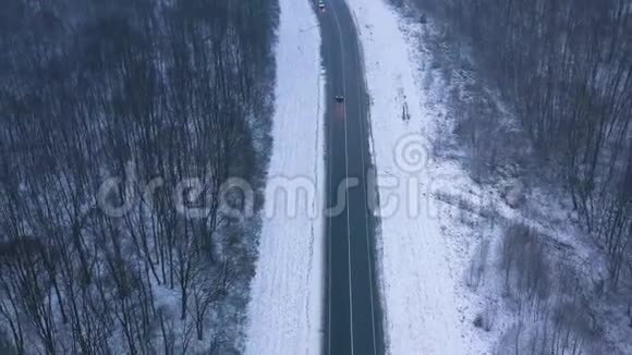 冬季穿过冬季森林的道路上的交通鸟瞰图视频的预览图