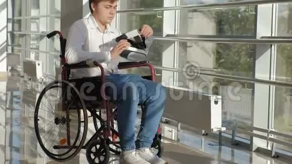 轮椅上的残疾人在窗户上使用虚拟现实头盔视频的预览图