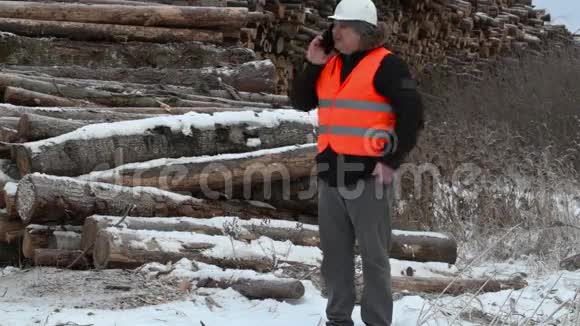 工程师在靠近成堆原木的智能手机上讲话视频的预览图