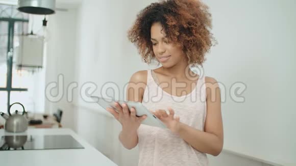 微笑快乐的美国妇女使用个人电脑平板电脑在家里视频的预览图