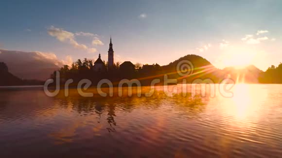 秋天的布莱德湖斯洛文尼亚的圣玛丽教堂在小岛上的水和美丽的日落视频的预览图