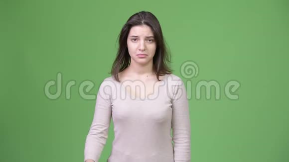 年轻悲伤的女人在绿色的背景下竖起大拇指视频的预览图