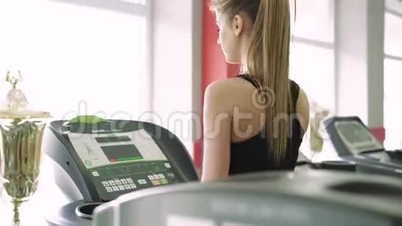 健身房跑步机上漂亮的金发女郎4k视频的预览图