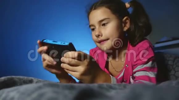 十几岁的女孩在玩手提电子游戏晚上在室内玩游戏机视频的预览图