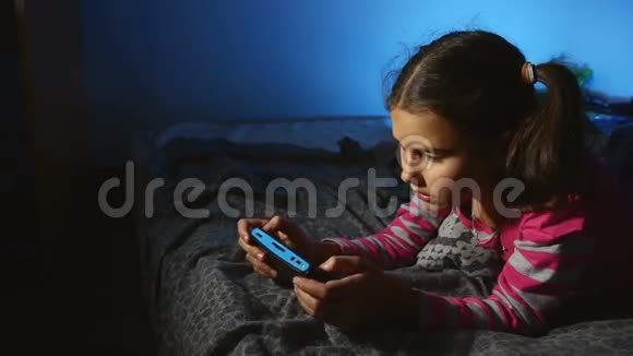 青少年女孩玩手提电子游戏一个控制台在线孩子晚上在室内视频的预览图