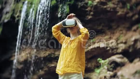 女孩虚拟现实眼镜VR晴天野生动物女人举手山瀑布森林电子视频的预览图