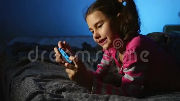 青少年女孩玩手提电子游戏一个控制台孩子在网上晚上在室内视频的预览图