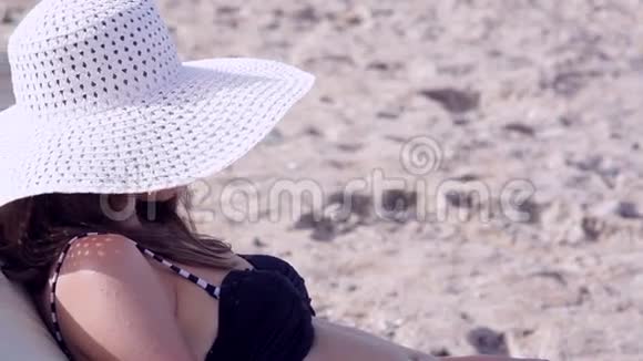戴着白色大帽子的漂亮女人在休息室里晒日光浴视频的预览图